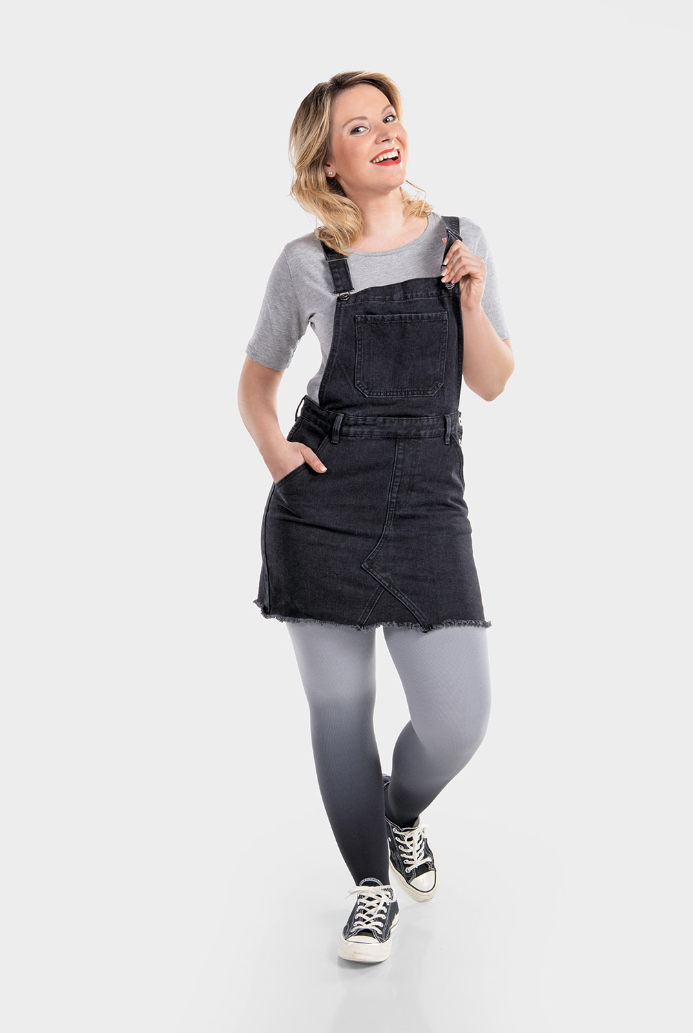 A woman is wearing a black pinafore dress and compression hosiery in dip-dye grey A woman is wearing a black pinafore dress and compression hosiery in dip-dye grey