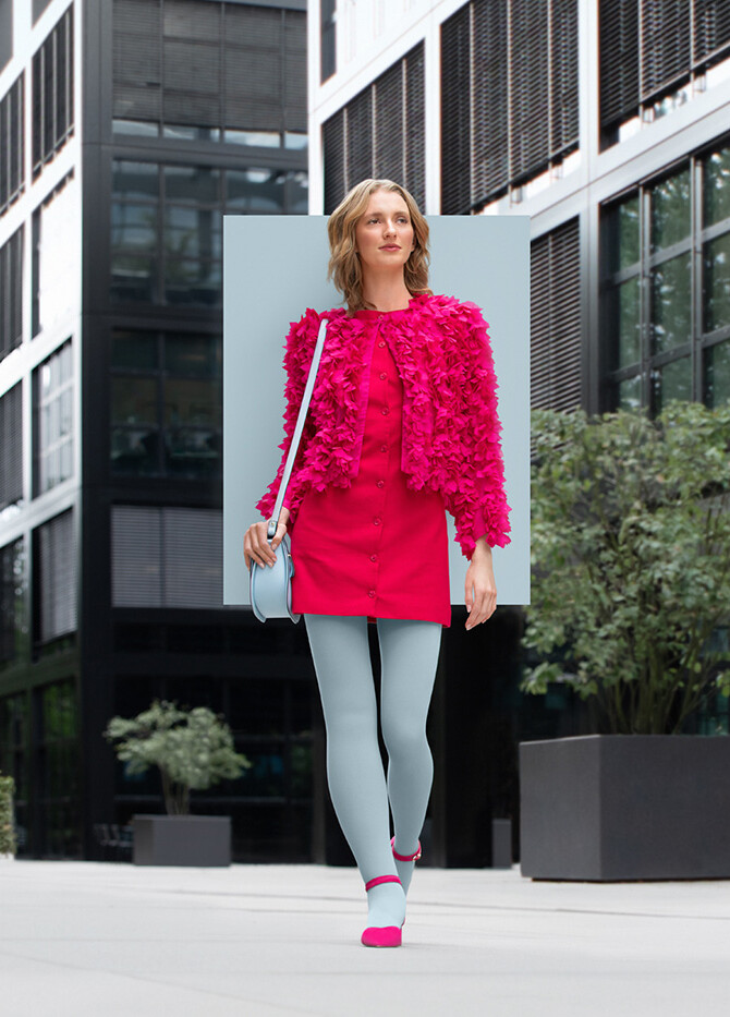 A woman with lymphoedema walks through the city wearing an Icy Blue compression garment with a pink dress