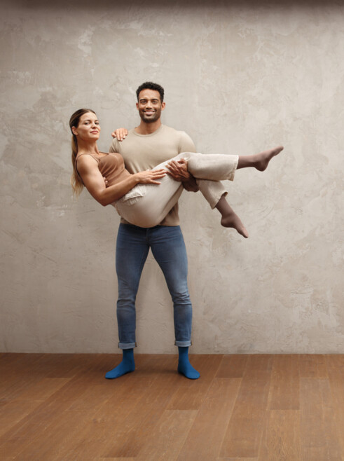 L'homme porte une femme dans ses bras, tous deux portent des bas Juzo Intenso