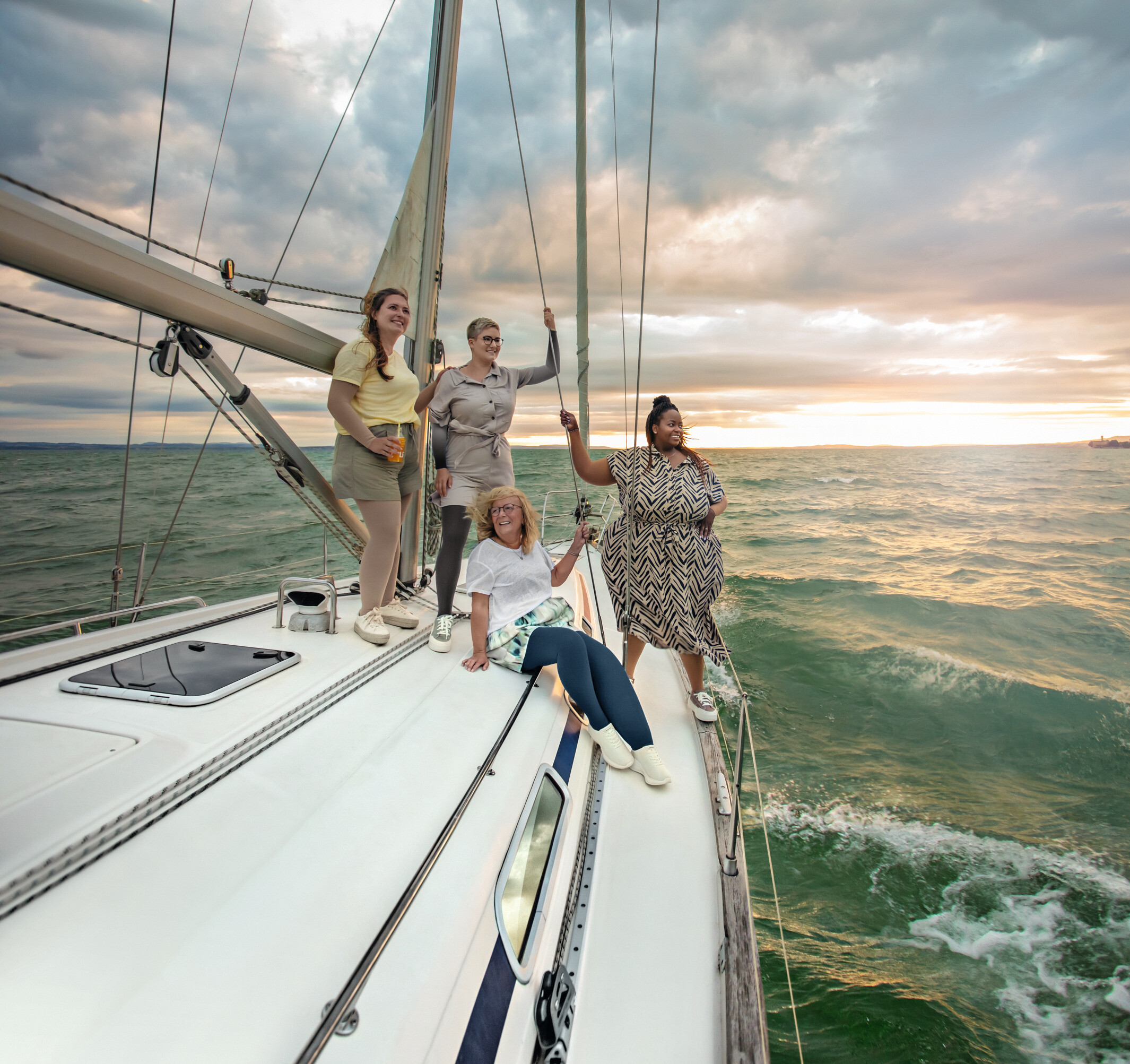 Personengruppe auf einem Segelboot bei Sonnenuntergang, mehrere tragen Kompressionsstrümpfe. Personengruppe auf einem Segelboot bei Sonnenuntergang, mehrere tragen Kompressionsstrümpfe.