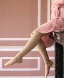 2. Lifestyle image Juzo Soft Woman with Juzo Soft Sesame sitting on a mantelpiece