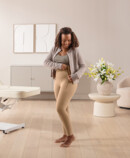 Lifestyle Juzo Comprima Leggins Eine dunkelhaarige Frau schließt gerade den Reißverschluss der Juzo Comprima Leggins